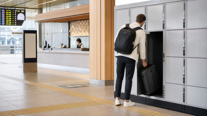 Traveler placing a suitcase in a large coin locker at a modern Japanese railway station