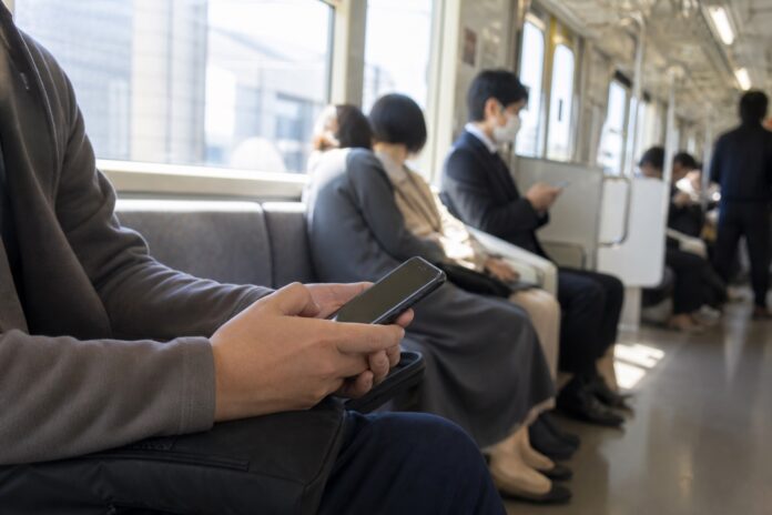 Passenger quietly using a smartphone inside a Japanese commuter train