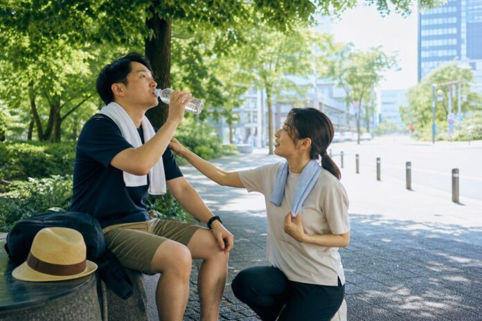 夏の木陰で水分補給と体温調整をする旅行者