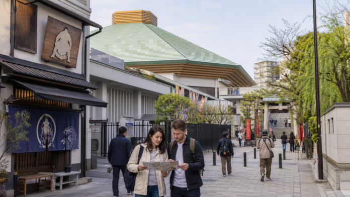 Travelers consult a neighborhood map while walking between sumo-inspired shops, the Ryogoku arena district and a small shrine